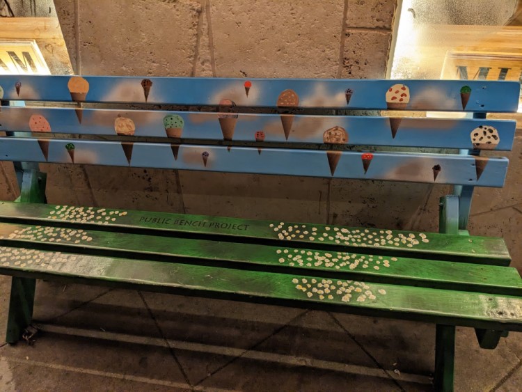 a bench painted with flying ice cream cones. There is text saying “Public Bench Project”