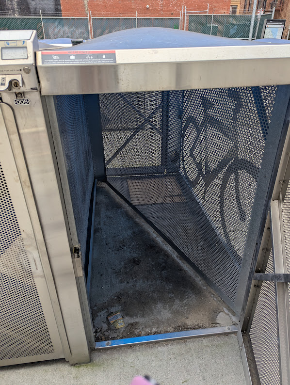 “The inside of a bike link locker. It is a long metal box divided in half triangularly.”