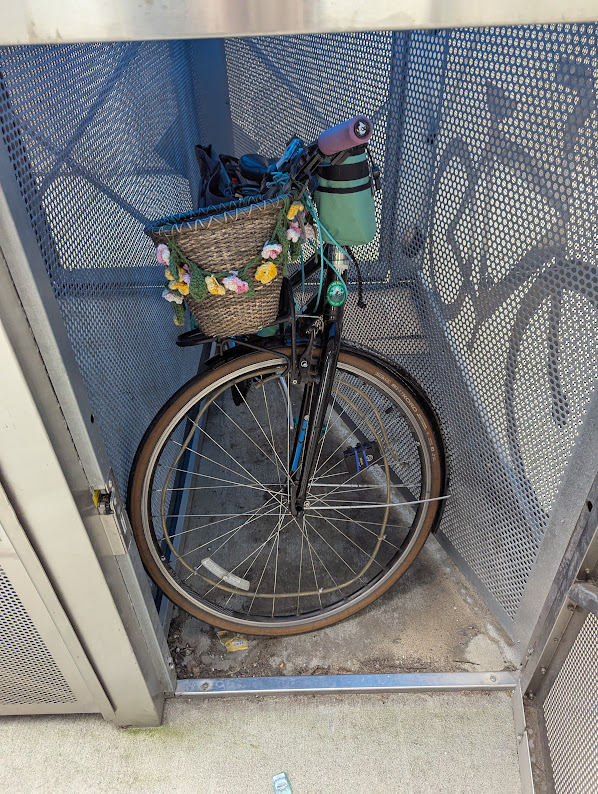 “The inside of a bike link locker. It now contains a bike with a basket, which barely fits with its wheel rotated.”